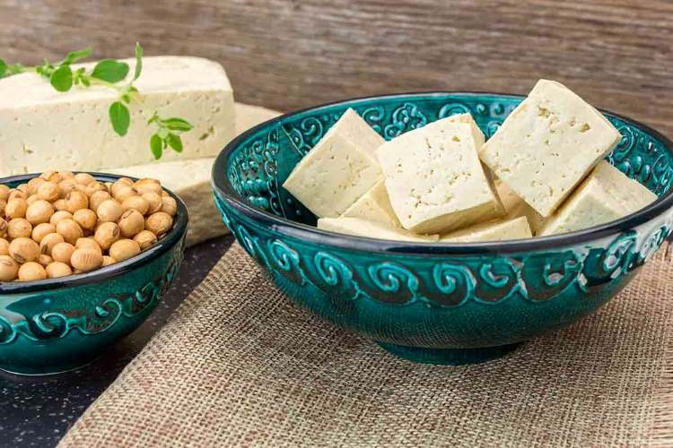 Como Fazer Tofu Firme em Casa Receita Completa, Dicas de Temperos e Valor Nutricional O tofu caseiro firme é uma excelente alternativa ao queijo tradicional, rico em proteínas, versátil e saudável. Feito a partir da soja, ele pode ser temperado de várias formas e até ganhar um sabor semelhante ao do queijo parmesão, usando ingredientes específicos. Neste guia completo, vamos ensinar como preparar tofu firme em casa, os temperos ideais para realçar o sabor e trazer uma tabela nutricional detalhada. Ingredientes para Fazer Tofu Firme Caseiro 500 g de grãos de soja amarela seca 2,5 litros de água filtrada (para bater e cozinhar) 1 litro de água para demolhar a soja 1 colher de sopa de nigari (cloreto de magnésio) ou suco de 1 limão (coagulante) 1 pano de algodão limpo ou gaze fina para coar 1 forma com peso (pode ser uma prensa de tofu ou improviso com recipiente e algo pesado) Ingredientes opcionais para sabor e textura 2 colheres de sopa de levedura nutricional (confere sabor semelhante ao queijo parmesão) 1 colher de chá de cúrcuma (para cor amarelada e leve sabor terroso) 1 colher de chá de sal marinho ou sal rosa Páprica defumada, pimenta-do-reino ou alho em pó (para versões temperadas) Como Fazer Tofu Firme em Casa (Passo a Passo) 1. Hidratar os grãos de soja Coloque os grãos de soja em uma tigela grande, cubra com água e deixe de molho por 8 a 12 horas. A soja irá dobrar de volume. 2. Preparar o “leite de soja” Escorra a água do demolho. Bata a soja hidratada no liquidificador com 2,5 litros de água filtrada até obter uma mistura homogênea. Coe a mistura usando um pano de algodão ou gaze, separando o leite de soja do resíduo sólido (okara). 3. Cozinhar o leite de soja Coloque o leite de soja em uma panela, leve ao fogo médio e mexa sempre até ferver. Cozinhe por 10 minutos para eliminar o sabor cru da soja. 4. Coagular o leite Dissolva o nigari (ou suco de limão) em 100 ml de água morna. Adicione aos poucos no leite de soja quente, mexendo suavemente. Em alguns minutos, a mistura começará a coalhar, formando grumos. 5. Moldar o tofu firme Coloque a mistura coalhada no pano de algodão dentro de uma forma. Feche o pano e coloque um peso por cima. Deixe descansar de 30 a 60 minutos, dependendo da firmeza desejada. Após prensado, desenforme e armazene em pote fechado com água filtrada na geladeira (troque a água diariamente). Como Deixar o Tofu com Sabor de Queijo Parmesão Se você gosta do sabor marcante de queijo, pode temperar o tofu ainda fresco ou já prensado com: Levedura nutricional (2 a 3 colheres de sopa) – sabor semelhante ao queijo parmesão; Azeite de oliva extravirgem – traz cremosidade; Alho em pó e cebola em pó – intensificam o sabor; Páprica defumada – dá um toque gourmet; Sal marinho ou missô – para realçar o sabor umami. Sugestões de Uso do Tofu Firme Caseiro Fatiado em sanduíches e saladas Grelhado com ervas e especiarias Em cubos para ensopados, sopas e yakissoba Como base para pastas e patês veganos Desfarelado para substituir a carne moída em receitas vegetarianas Tabela Nutricional do Tofu Firme (100 g) Nutriente Quantidade aproximada Calorias 76 kcal Proteínas 8 g Gorduras totais 4,8 g - Gorduras saturadas 0,7 g Carboidratos 1,9 g Fibras alimentares 0,3 g Cálcio 350 mg Magnésio 30 mg Ferro 1,6 mg Potássio 120 mg (Valores aproximados, podendo variar conforme preparo e coagulante usado) Benefícios do Tofu Caseiro Rico em proteínas vegetais – ideal para vegetarianos e veganos. Fonte de cálcio e ferro – importante para ossos e circulação. Baixo em calorias e gorduras saturadas – ótimo para dietas de emagrecimento. Versátil – aceita vários temperos, podendo substituir queijos e carnes em diversas receitas. Sem lactose e sem glúten – indicado para intolerantes e alérgicos. Conclusão Fazer tofu firme caseiro é mais simples do que parece e oferece inúmeras possibilidades na cozinha. Além de econômico, é uma opção saudável, proteica e versátil. Com a adição de levedura nutricional, o tofu pode até lembrar o sabor marcante do queijo parmesão, tornando-se ainda mais atrativo. Seja para receitas salgadas, grelhados ou pastas, o tofu feito em casa garante frescor, qualidade e sabor incomparáveis.